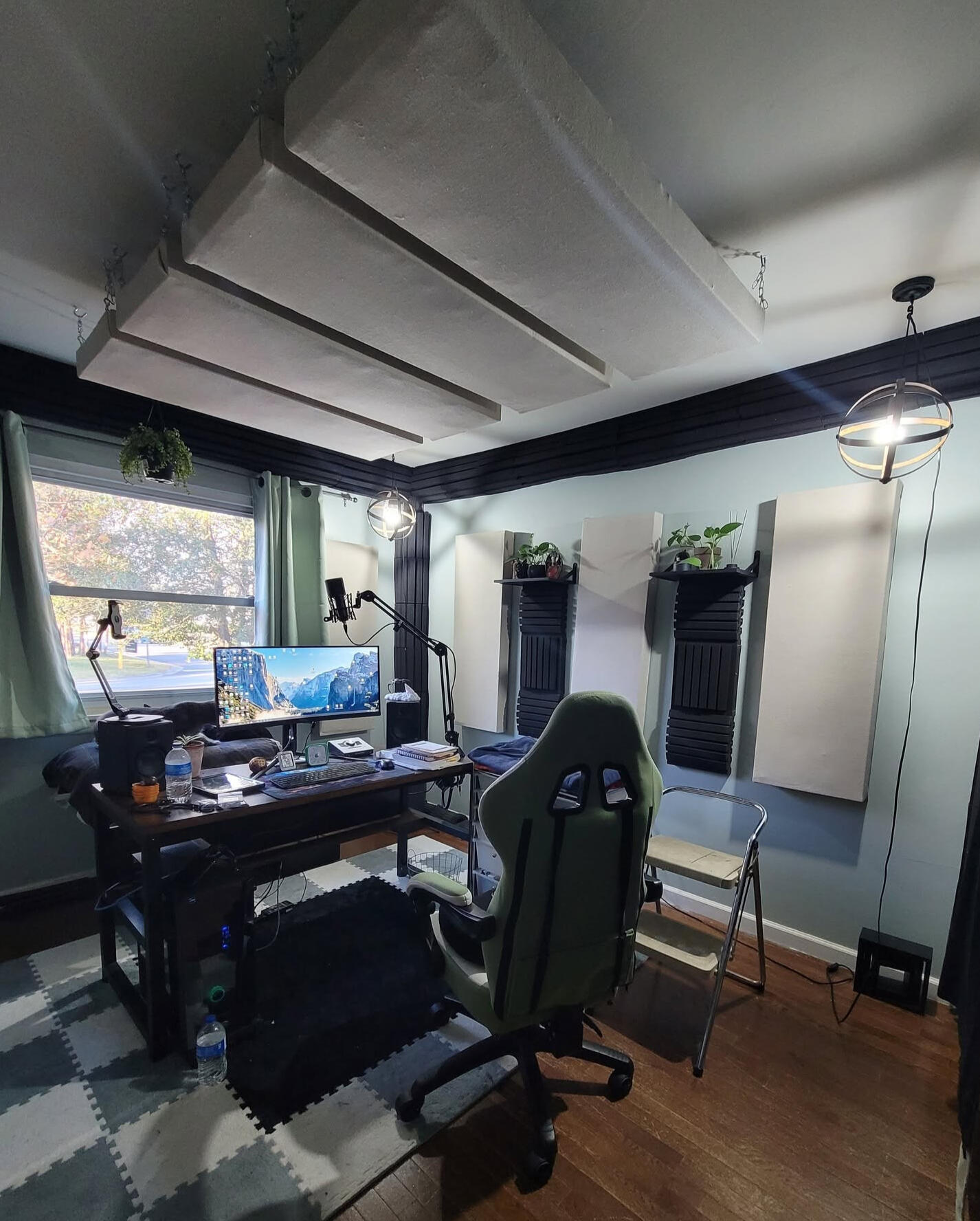 New Studio A sound treated studio with sage colored sound dampening curtains, Canvas colored sound panels, black base traps and thick acoustic foam, an desk 1/3 center placement with audio equipment for optimal sound.